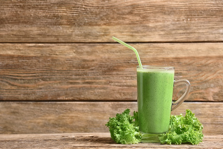 Glass of fresh vegetable smoothie on wooden backgroundの写真素材
