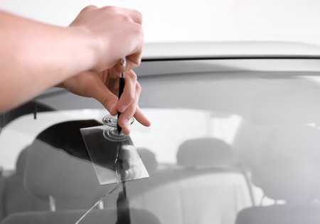 Specialist fixing crack on car windshield in repair shopの写真素材