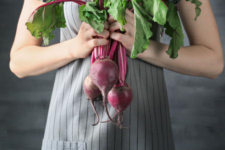 Woman holding young beets on grey backgroundの写真素材