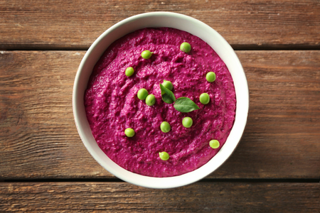 Bowl with delicious creamy beet hummus on wooden backgroundの写真素材