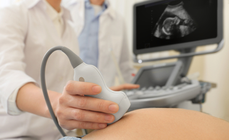 Doctor conducting ultrasound examination of pregnant woman in clinic, closeupの写真素材