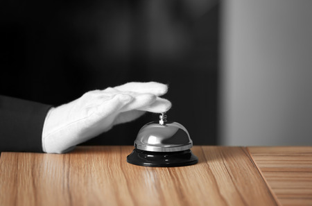 Man ringing service bell on wooden table