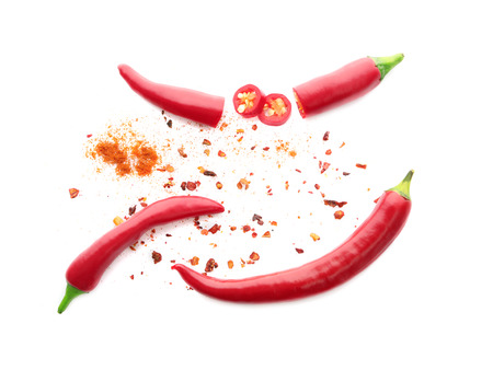 Whole and sliced red chili peppers pods with seeds isolated on white