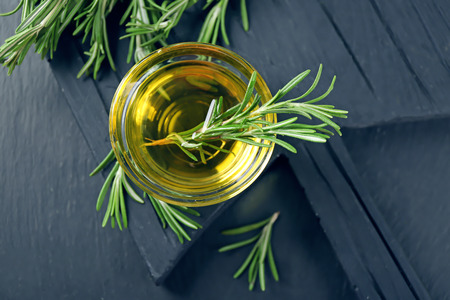 Bowl with rosemary oil and herb on wooden boardの写真素材
