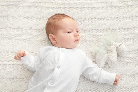 Cute little baby lying on soft plaid at homeの写真素材