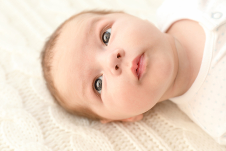Cute little baby lying on soft plaid at homeの写真素材