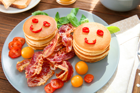 Creative tasty breakfast with pancakes and bacon on tableの写真素材