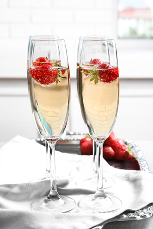 Glasses of delicious wine with strawberry on tableの写真素材