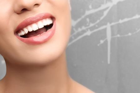 Young woman with healthy teeth laughing on grey background, closeupの写真素材