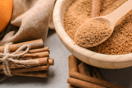 Cinnamon sticks and sugar in wooden bowl with spoon on grey background, closeupの写真素材
