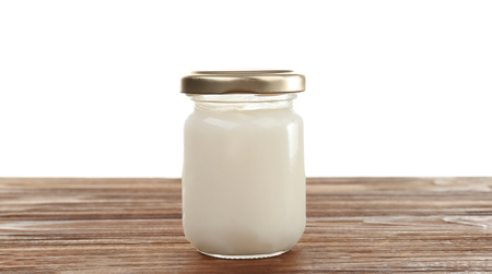 Coconut oil in mason jar on table against white backgroundの写真素材