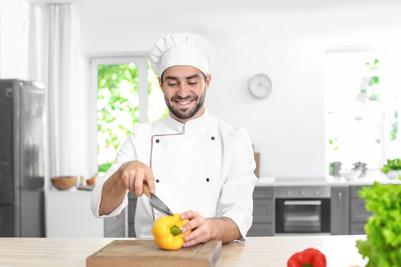 Young male chef cutting paprika in kitchenの写真素材