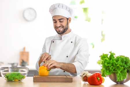 Young male chef cutting paprika in kitchenの写真素材