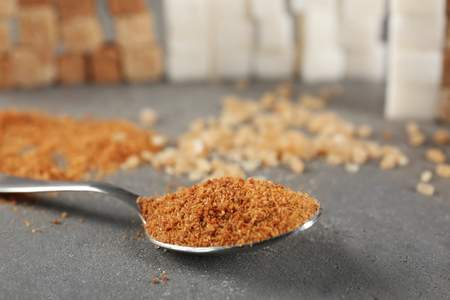 Spoon of brown sugar on grey tableの写真素材