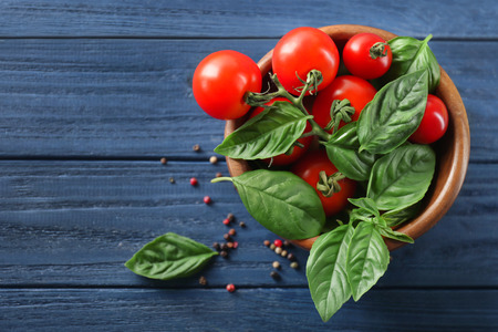 Cherry tomatoes and green fresh organic basil on wooden backgroundの写真素材