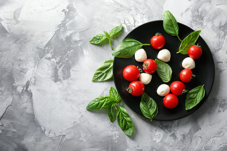 Mozzarella cheese balls, cherry tomatoes and green fresh organic basil on grey backgroundの写真素材