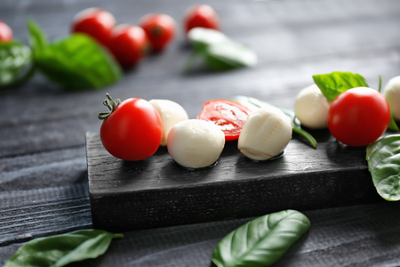 Mozzarella cheese balls, cherry tomatoes and green fresh organic basil on wooden backgroundの写真素材