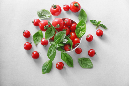 Cherry tomatoes and green fresh organic basil on light backgroundの写真素材