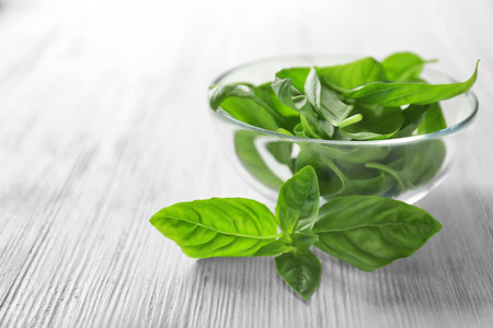 Green fresh organic basil leaves in glass bowl on wooden backgroundの写真素材