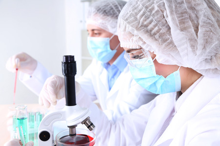 Male and female scientists using microscope in laboratoryの写真素材