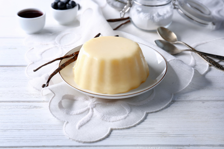 Plate with delicious vanilla pudding on wooden tableの写真素材
