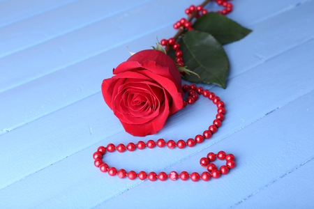 Beautiful red rose with beads on color wooden planks backgroundの写真素材