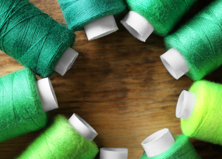 Many threads of different green shades on wooden background