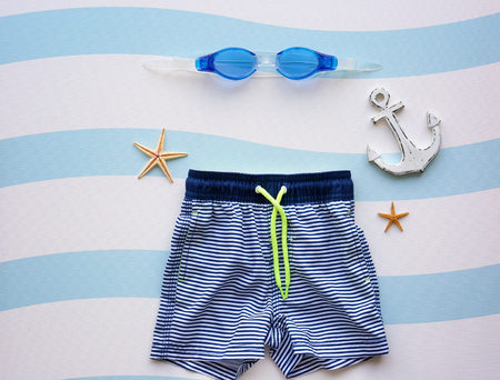 Swimming trunks of boy and goggles on color backgroundの写真素材