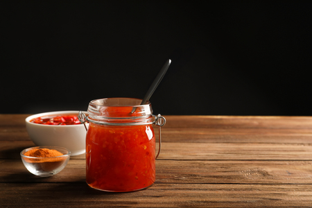 Delicious chili sauce in kitchenware on wooden tableの写真素材