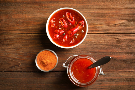 Delicious chili sauce in kitchenware on wooden tableの写真素材