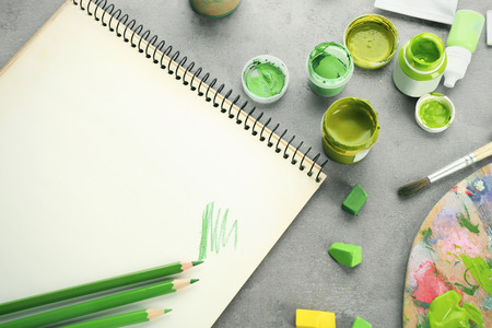 Composition with green pencils, notebook and chalks on tableの写真素材