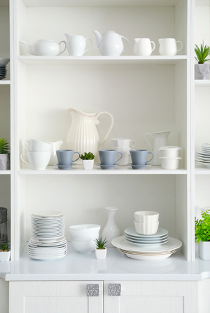 White storage stand with ceramic dishware in kitchenの写真素材