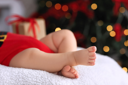 Cute little baby sleeping against blurred Christmas lights backgroundの写真素材
