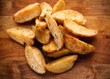 Delicious baked potato wedges on wooden backgroundの写真素材