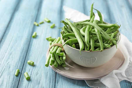 Bowl and fresh green beans on wooden backgroundの写真素材