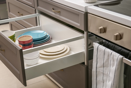 Set of tableware in kitchen drawer near ovenの写真素材