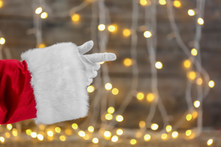 Santa Claus hand against blurred Christmas lightsの写真素材