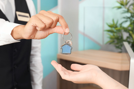 Male receptionist giving room key to client in hotelの写真素材