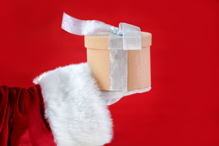 Santa Claus holding gift box against red backgroundの写真素材