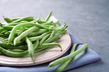 Plate with fresh green beans on table