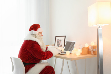 Authentic Santa Claus using laptop at tableの写真素材