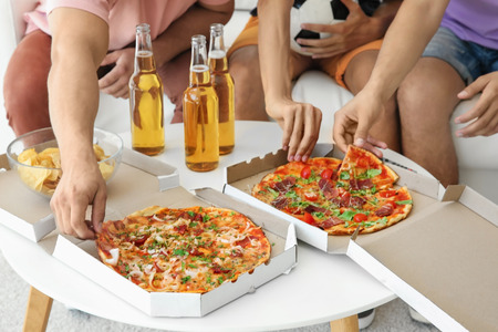 People eating pizza at home. Watching TV conceptの写真素材