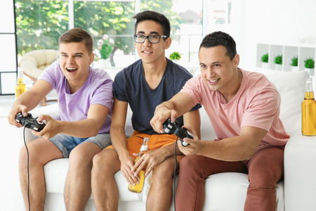 Young men playing video games on TV at homeの写真素材
