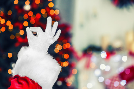 Santa Claus hand against blurred Christmas lightsの写真素材