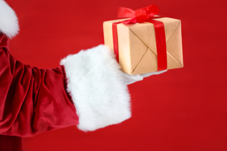 Santa Claus holding gift box against red backgroundの写真素材