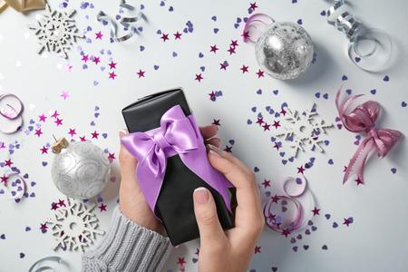 Female hands holding gift box on white sparkling backgroundの写真素材