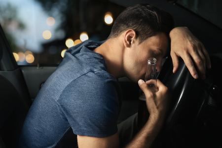 Man drinking alcohol in carの写真素材