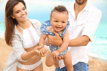 Happy couple with little daughter on beach