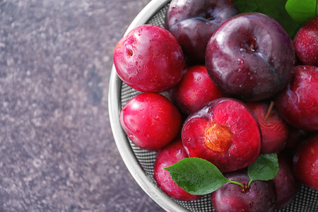 Sieve with fresh ripe plums on table, closeupの写真素材