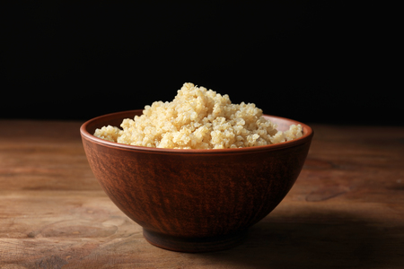 Bowl with boiled white quinoa grains on wooden tableの写真素材